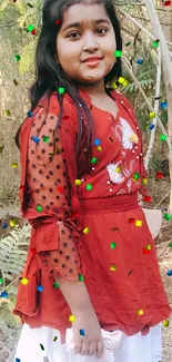 Woman in red dress standing outdoors against a scenic natural backdrop.