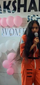 Girl in orange spacesuit with balloons backdrop.