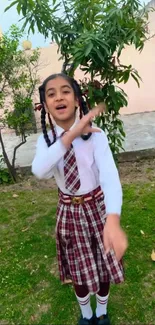 Young girl in school uniform with green outdoor background.