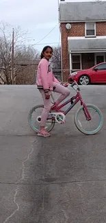 Girl riding a bicycle on a suburban street, surrounded by cars and houses.