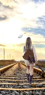 Girl with guitar walking on railway track at sunset.