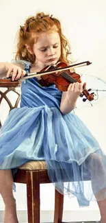 Young girl in blue dress playing violin on chair.