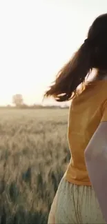 A girl in a yellow shirt running through a sunlit wheat field.