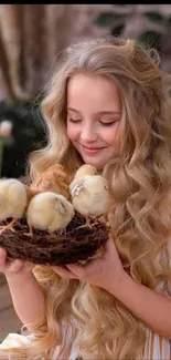 Girl with long hair holding baby chicks in a nest.