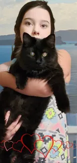 Girl holding a black cat with a scenic ocean backdrop.