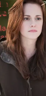 A girl with long brown hair in a dark jacket on a soft background.