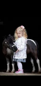 Little girl with pony against black background.