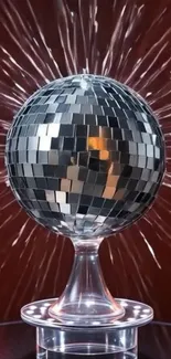 A dazzling disco ball with radiant sparkles against a red background.