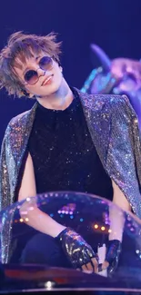 Performer on stage in sequined attire and sunglasses.