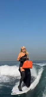 Woman surfing with an orange handbag in blue ocean.