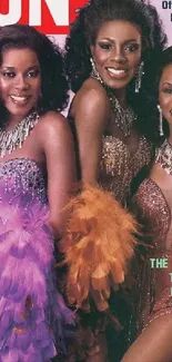 Three women in sparkling gowns with vibrant feathers pose elegantly.