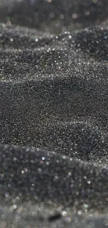 Black sand with glittering texture creating a dark, elegant mobile wallpaper.