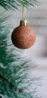 Copper ornament hanging on a green Christmas tree branch.