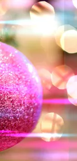 Pink ornament with glitter and bokeh lights in festive background.