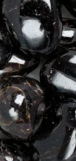 Glossy black stones with a shiny surface texture.