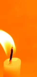 A glowing candle against an orange background.