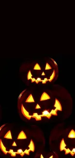 Glowing Halloween pumpkins stacked on a dark background.