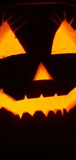 Glowing jack-o'-lantern with sharp, fiery features against a dark background.