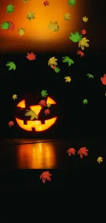 Halloween wallpaper with glowing pumpkin and colorful floating leaves.