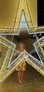 Woman standing inside a glowing star light display at night.