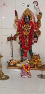 Goddess Kali statue adorned with vibrant red garlands.