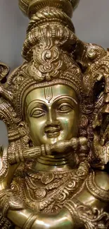 Gold Krishna statue with flute and intricate detailing on display.