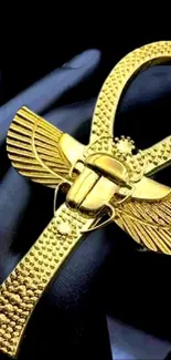 Golden ankh with wings on a dark background, symbolizing Egyptian heritage.