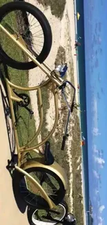 Golden cruiser bike resting on sunny beach path by the sea.