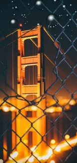 Golden Gate Bridge illuminated at night behind a chain-link fence.