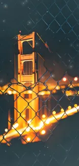 Golden illuminated bridge viewed through a wire fence at night.