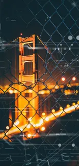 Night view of a golden bridge through a chain-link fence with city lights.