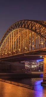 Golden bridge at night with reflection and urban lights.