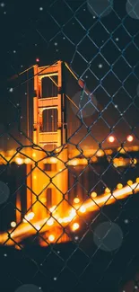 Golden Gate Bridge at night seen through a wire fence.