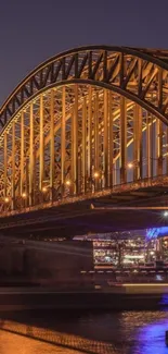 Golden bridge illuminated at night over a calm river.