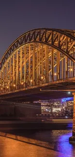 A golden-lit bridge at night over water, reflecting city lights.