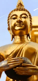 Golden Buddha statue with serene blue sky backdrop.