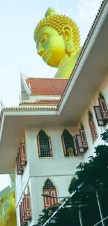 Golden Buddha statue behind temple facade in an urban setting.