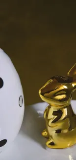 Glossy golden bunny next to black and white dice on a mobile wallpaper.