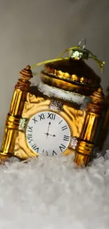 Golden clock ornament in snow with winter theme.