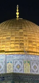 Golden dome of a mosque with intricate blue tile details at night.