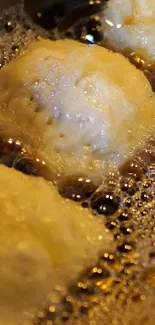 Close-up of golden dough balls frying in oil.