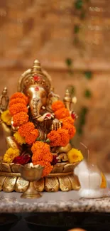 Golden Ganesha adorned with marigold flowers on a textured background.