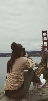 Person photographing the Golden Gate Bridge from a scenic viewpoint.