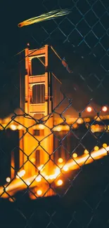 Golden Gate Bridge glowing warmly through a mesh fence at night.