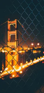 Golden Gate Bridge at night through a fence.