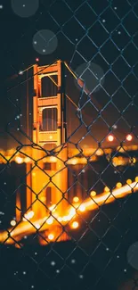 Golden Gate Bridge at night through a fence.