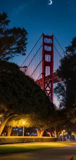 Golden Gate Bridge during night with crescent moon and illuminated trees.