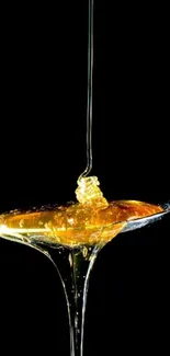 Mobile wallpaper with golden honey dripping from a spoon on black background.