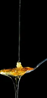 Golden honey flowing onto a spoon with black background.