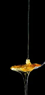 Golden honey dripping from a spoon on a black background.